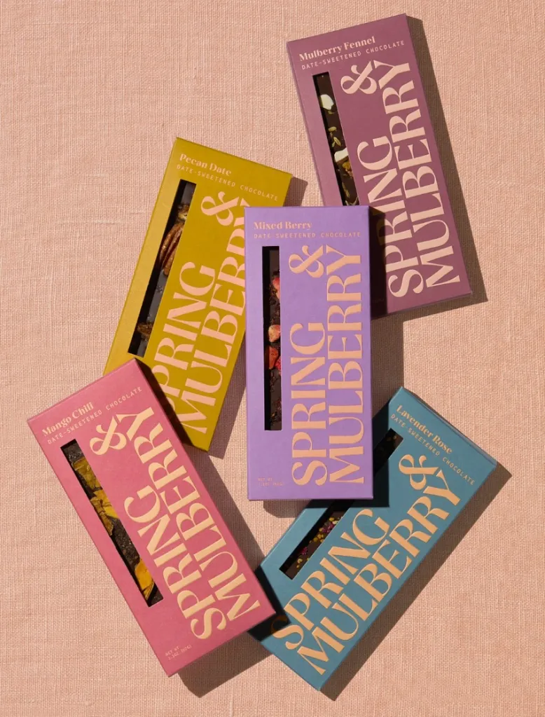 Five bars of Spring & Mulberry date-sweetened chocolate in assorted flavors and colorful packaging.