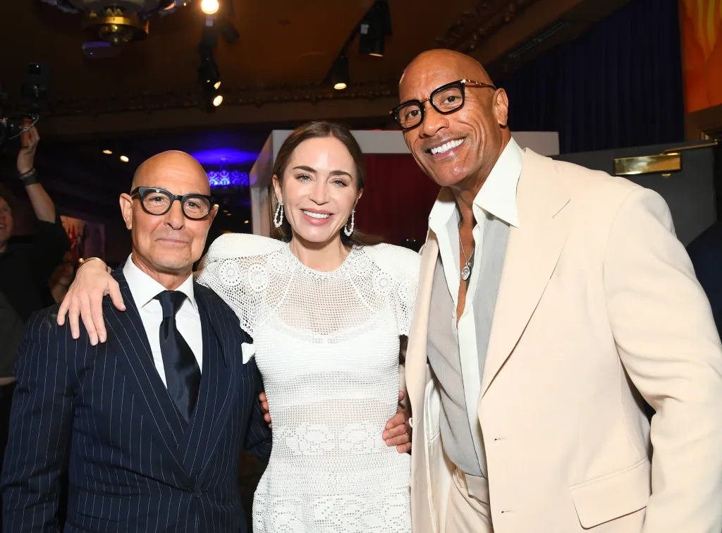 Stanley Tucci, Emily Blunt, and Dwayne Johnson posing for a photo.