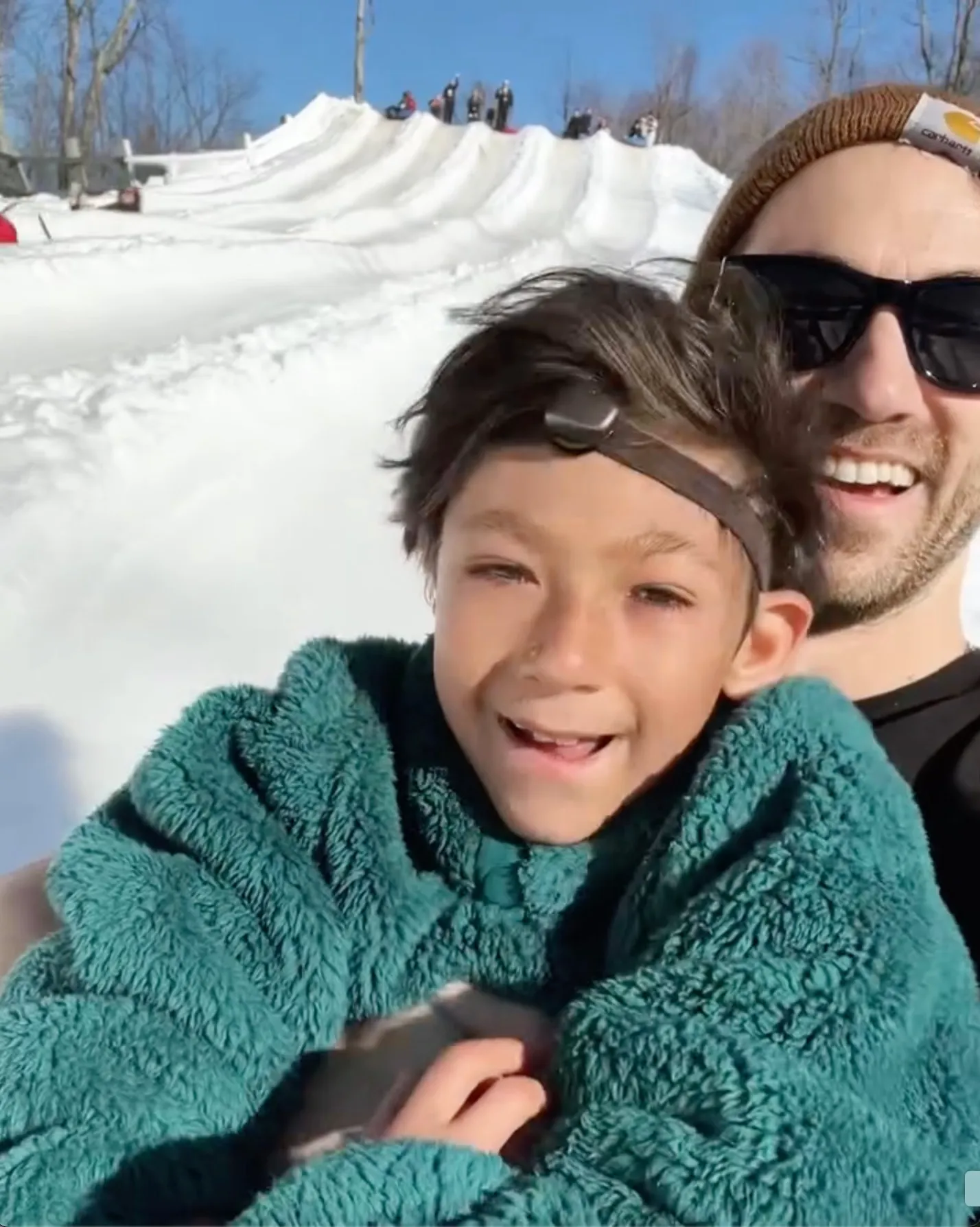 Daniel Coleman and his son Isaac smile while snow tubing.