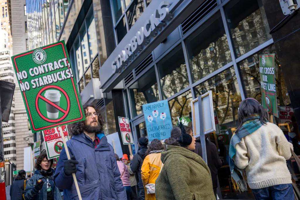 Starbucks workers protest outside a store with signs saying 