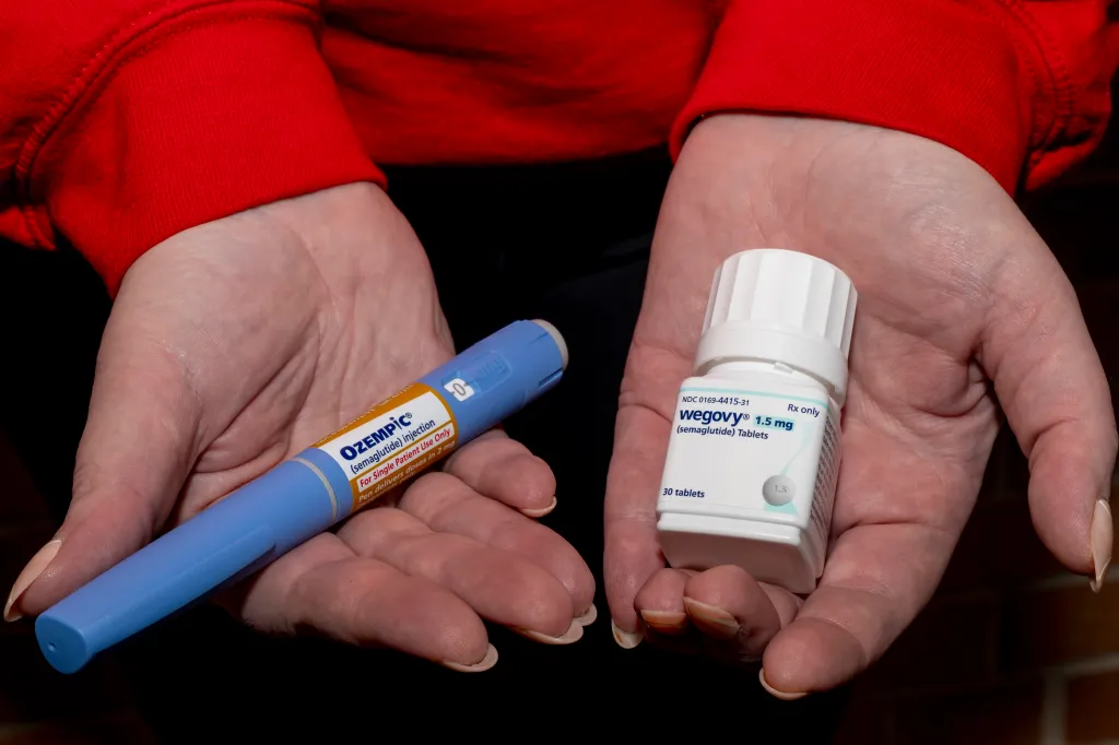 A woman’s hands hold an Ozempic semaglutide injection pen and a bottle of Wegovy semaglutide tablets.