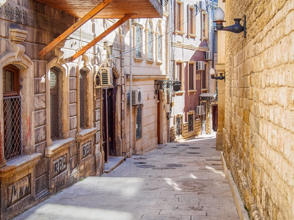 A narrow, empty street in Baku's Old Town, with ancient buildings and stone walls.