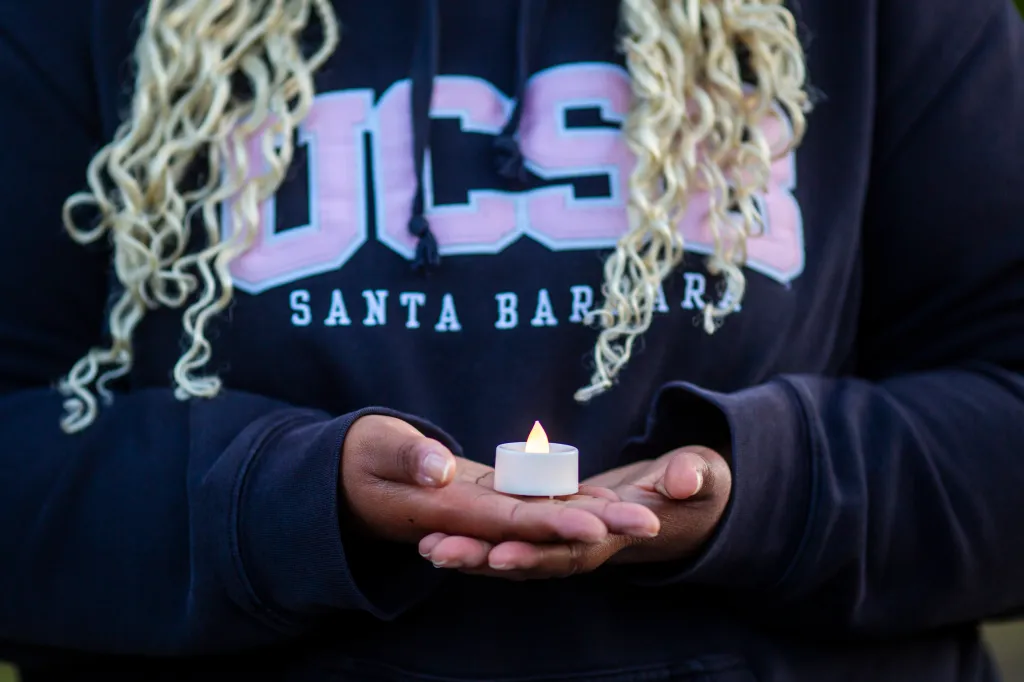 Student holding a candle during a vigil for a sexual assault survivor at UC Santa Barbara.
