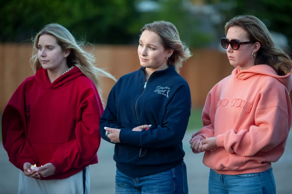Students Taylor Benke, Emmalyn Westlund and Valerie Tan hold candles at a vigil.