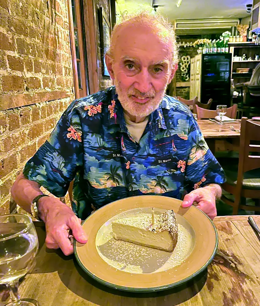Ross Falzone holding a slice of cheesecake in a restaurant.
