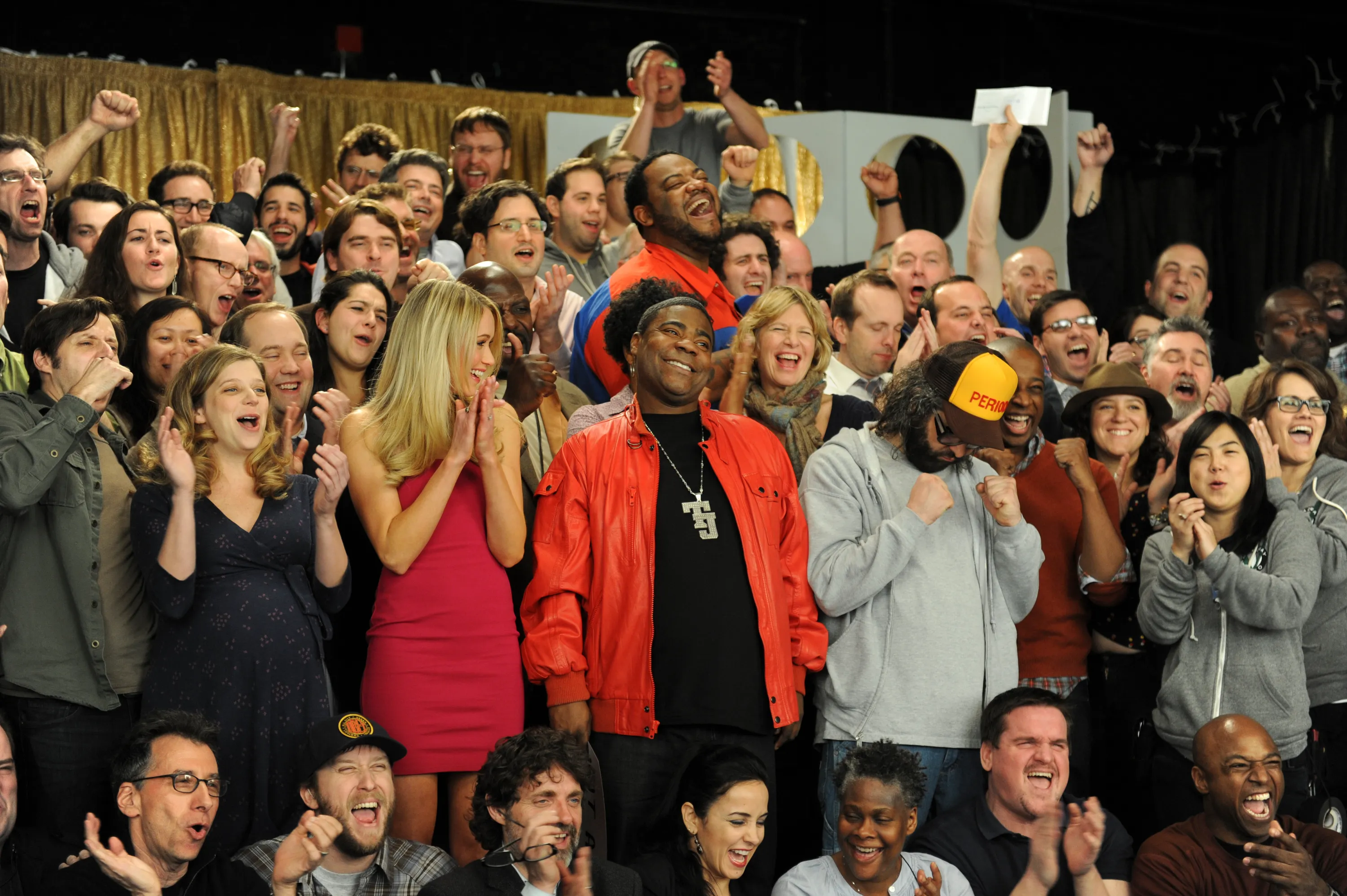 The cast of 30 Rock, including Tracy Morgan, Sue Galloway, John Lutz, Katrina Bowden, Kevin Brown, Judah Friedlander, Grizz Chapman, and Keith Powell, cheer and clap behind the scenes.