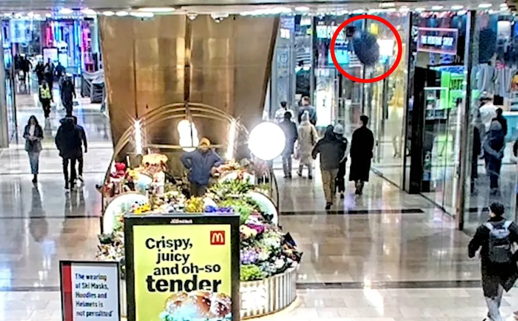 CCTV footage of a sofa falling from a shopping center balcony, highlighted by a red circle, narrowly missing shoppers below.