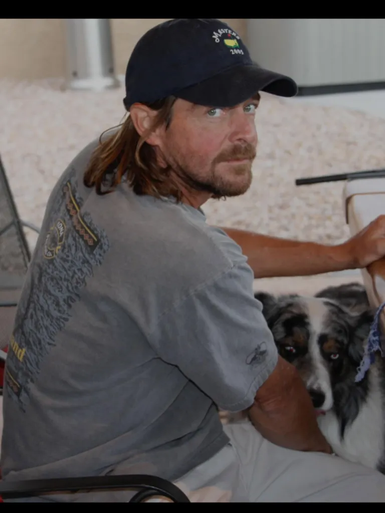 Jeff Probst's brother, Scott, wearing a cap and gray t-shirt, sitting next to a dog.