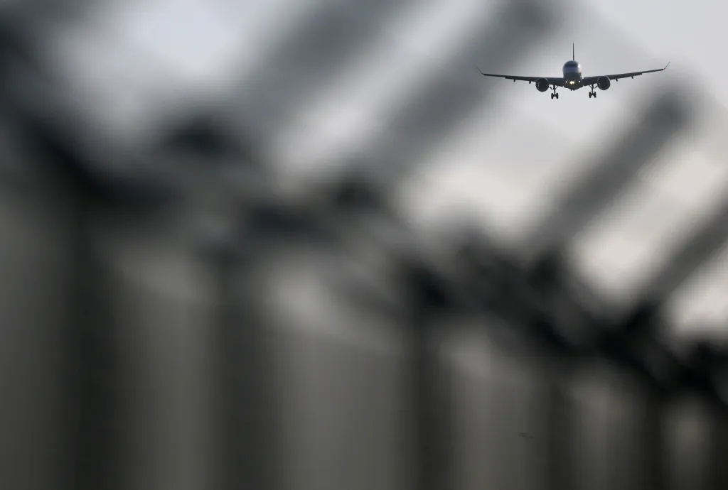 A Swiss Airlines aircraft prepares to land at Brussels International Airport, with a blurred fence in the foreground.