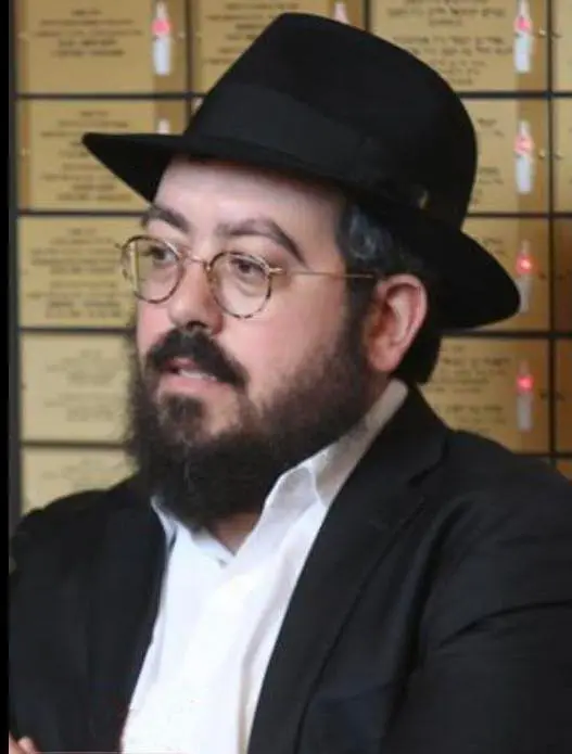 Rabbi Eli Schlanger wearing a fedora and glasses.