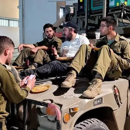 Rabbi Eli Schlanger sharing a meal and conversation with soldiers.