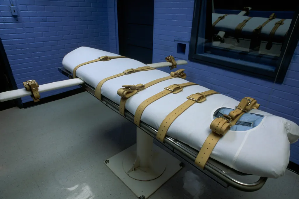 An empty medical gurney with multiple leather restraints on a mattress, in the Lethal Injection Room at Huntsville Unit prison.