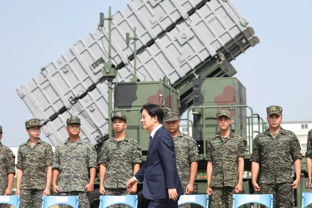 Taiwanese President Lai Ching-te walks past soldiers and military equipment at a naval base.
