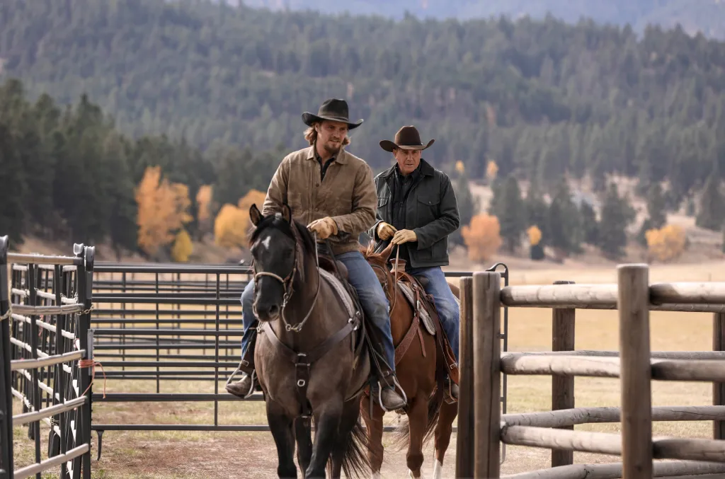 Luke Grimes as Kayce Dutton and Kevin Costner as John Dutton riding horses in Yellowstone.