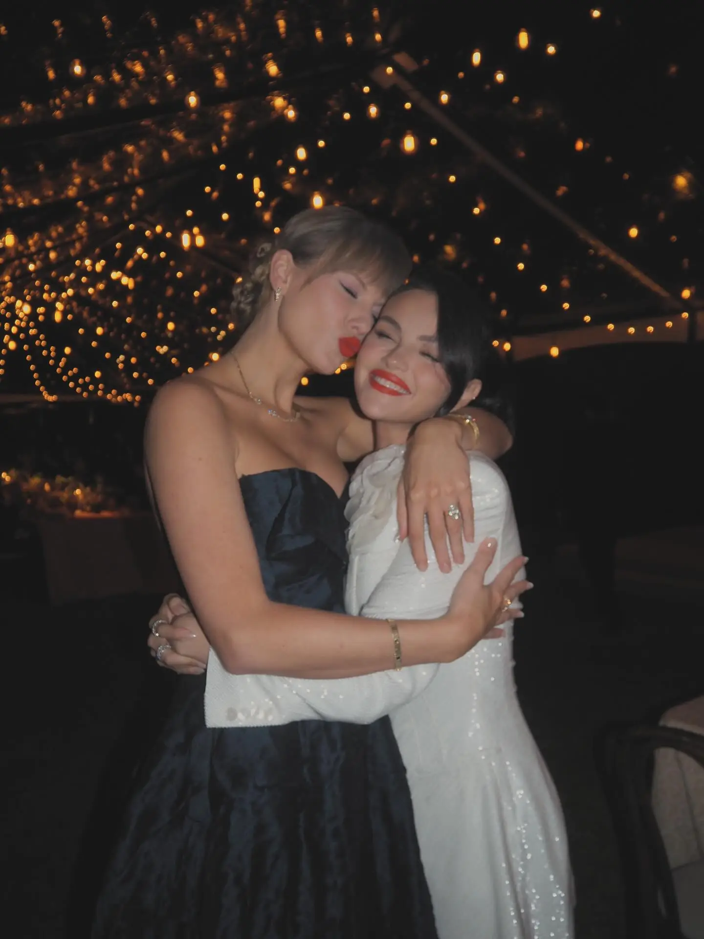 Taylor Swift kissing Selena Gomez on the cheek at a wedding.