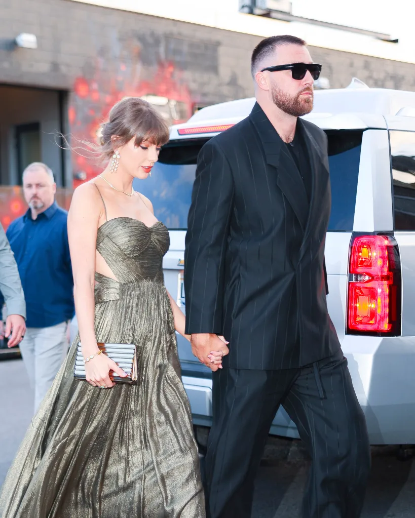 Taylor Swift in a gold gown and Travis Kelce in a dark pinstripe suit holding hands in New York City.