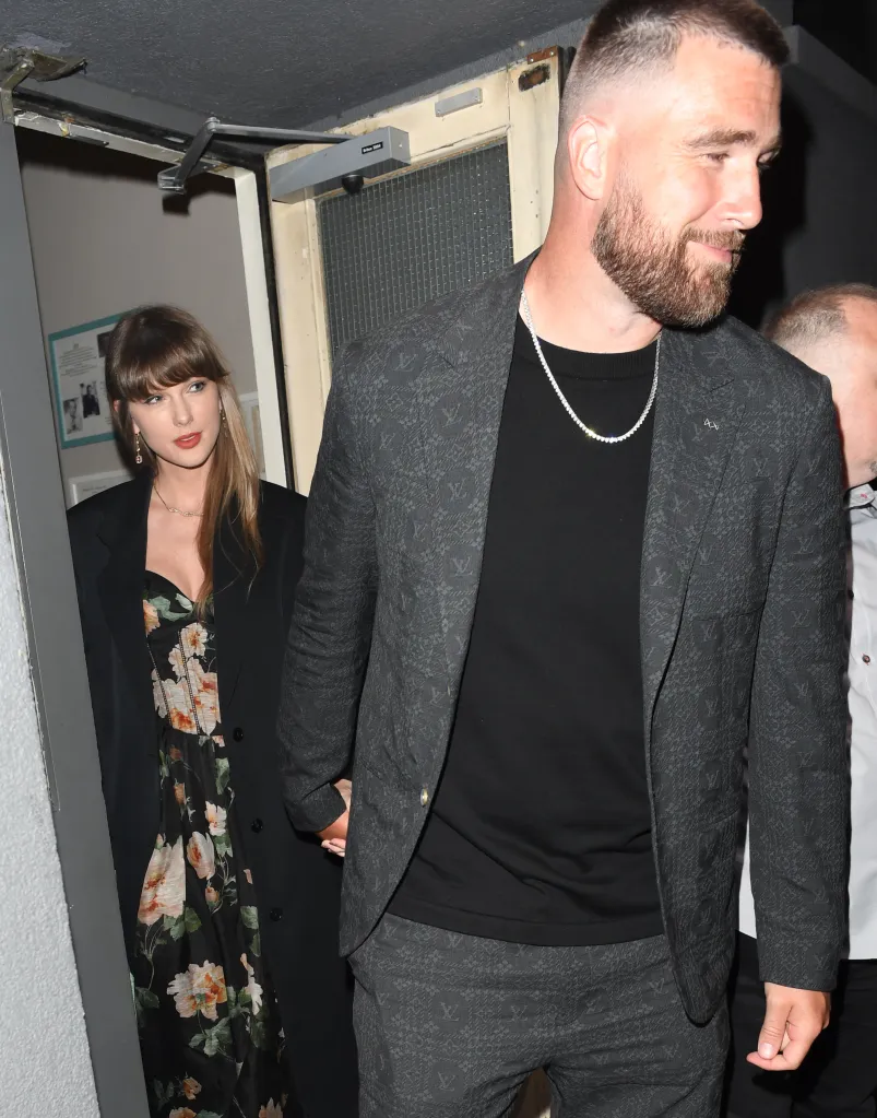 Taylor Swift in a black floral dress and Travis Kelce in a dark gray Louis Vuitton suit leave a theater.