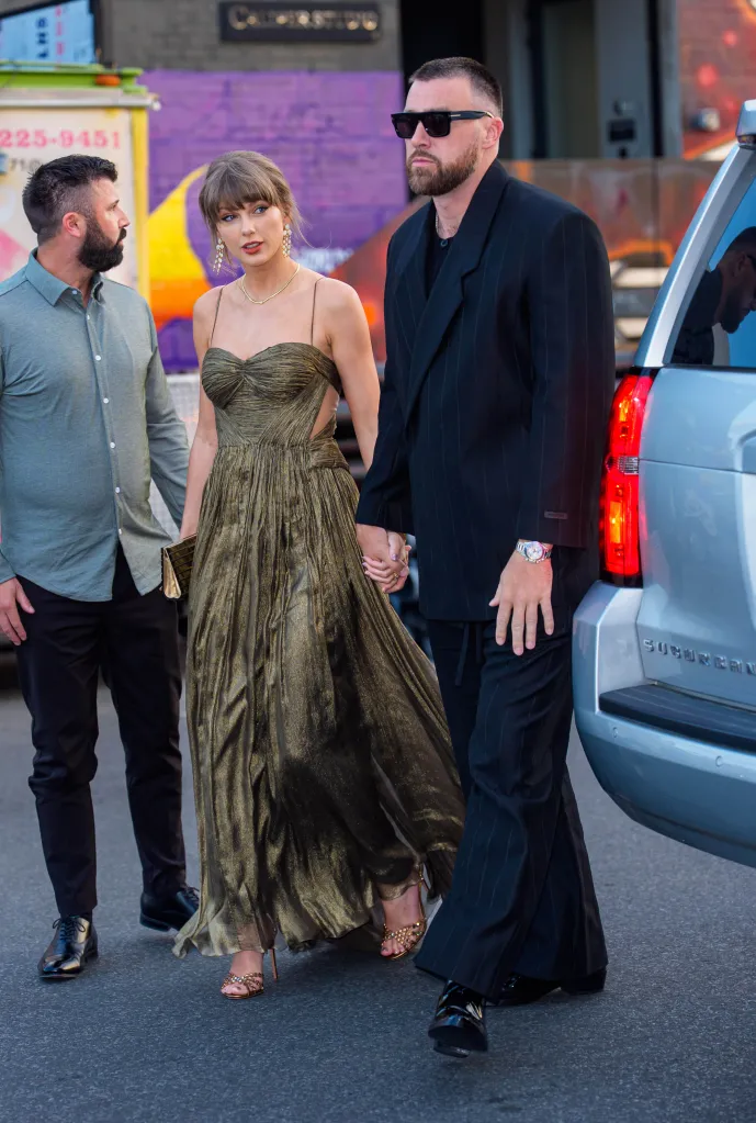 Taylor Swift and Travis Kelce holding hands while walking, with a man in a green shirt beside them and a silver car to the right.