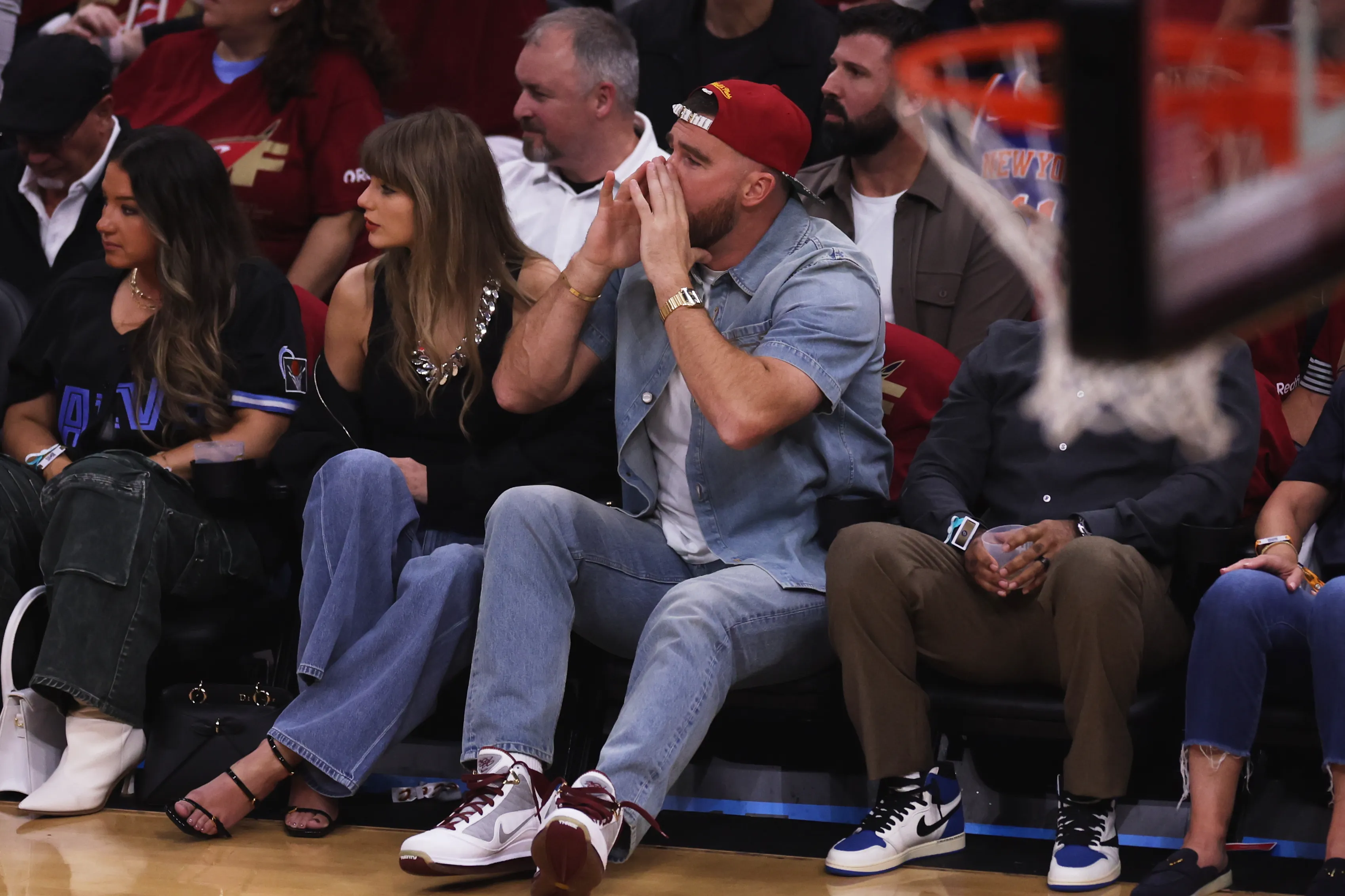 Taylor Swift and Travis Kelce watch an NBA basketball game from court-side seats.