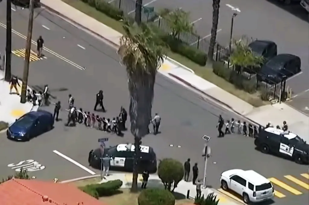 Aerial view of children in a line being evacuated with police officers on a street in San Diego.