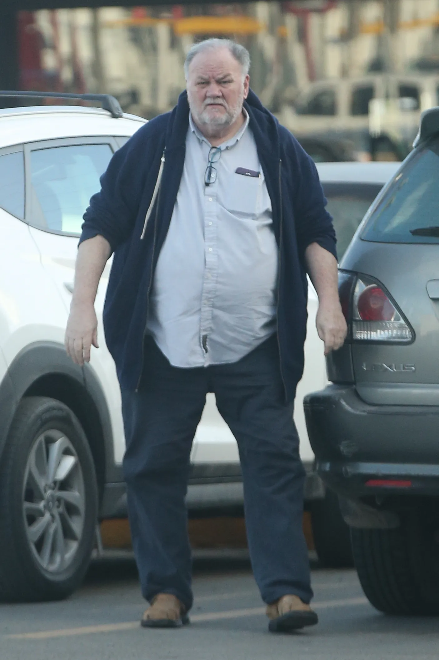 Thomas Markle walking past parked cars.
