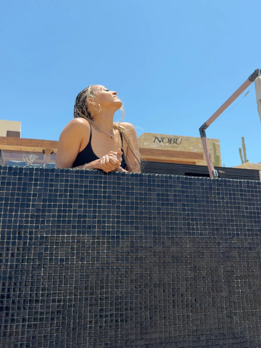 Tia Mowry looks upward with her hands clasped, enjoying a sunny day.