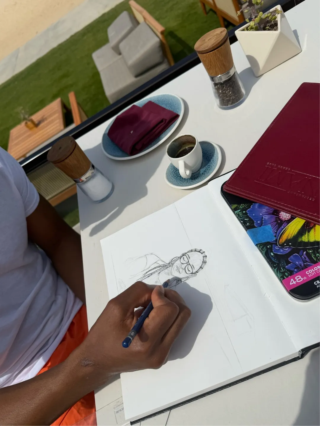 A person's hand sketching a portrait of Tia Mowry.