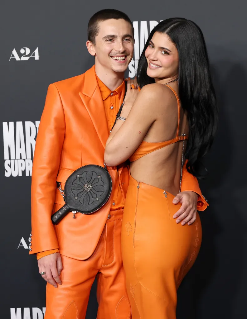 Timothée Chalamet and Kylie Jenner pose in matching orange outfits.
