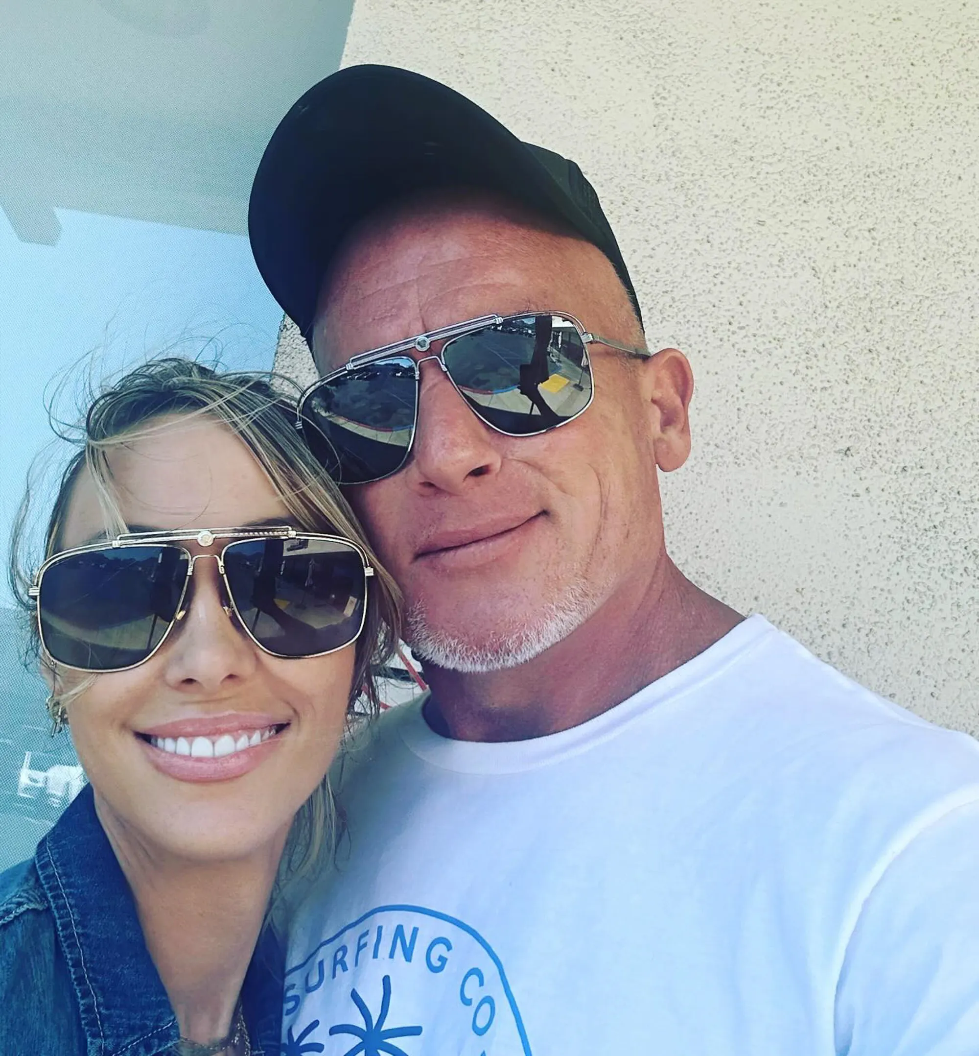 Tish Cyrus and Dominic Purcell smiling in sunglasses.