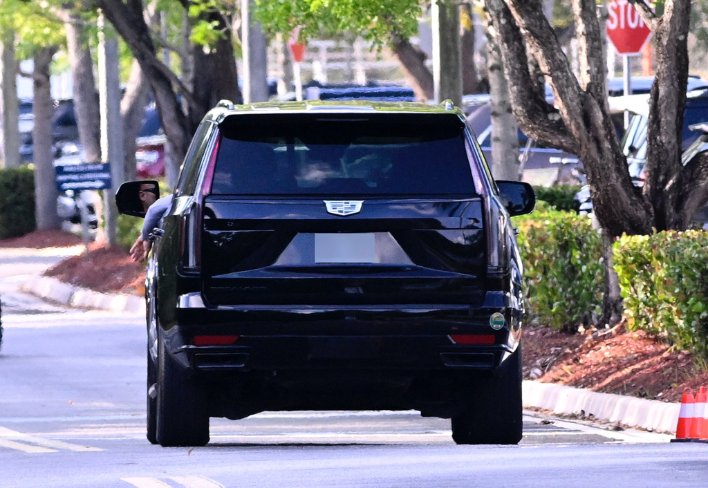 A person in a black Cadillac SUV, with their arm visible out the window, is leaving Blackbird Modern Asian restaurant after Kai Trump's graduation celebration in Jupiter, Florida.