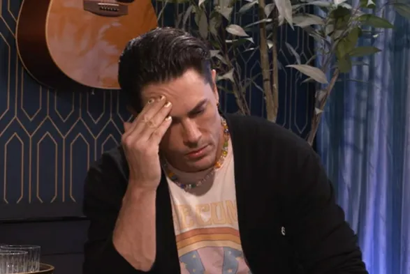 Tom Sandoval looking stressed, holding his hand to his forehead.