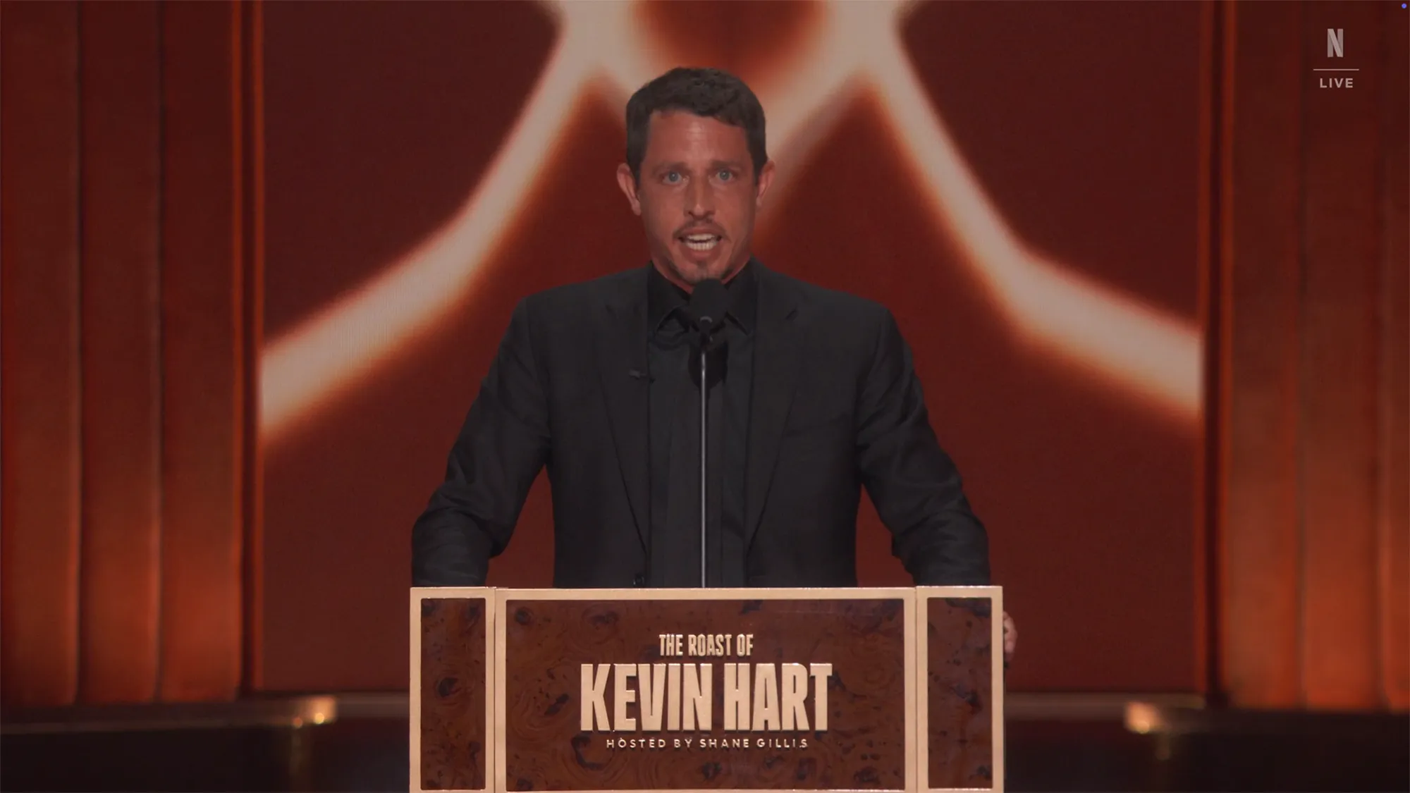 Tony Hinchcliffe standing at a podium labeled 