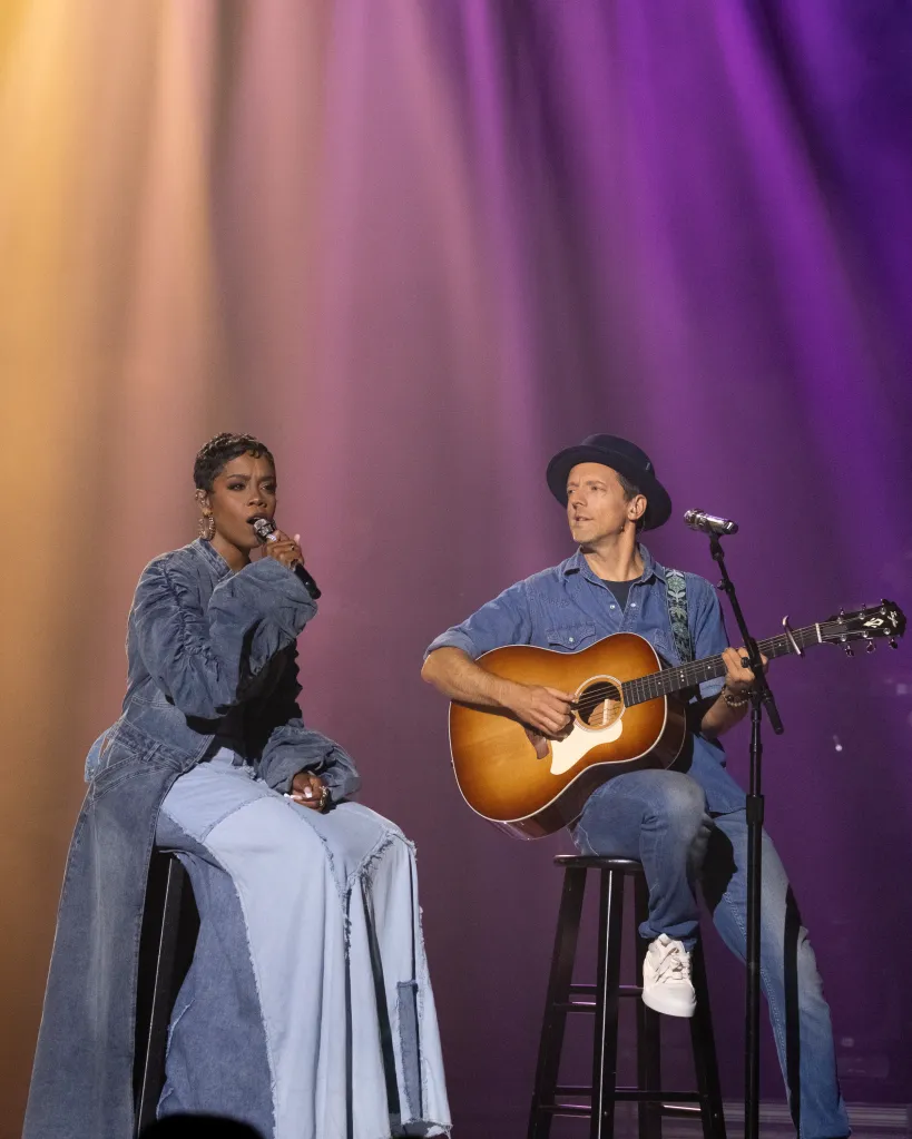 Keyla Richardson singing into a microphone next to Jason Mraz playing an acoustic guitar.