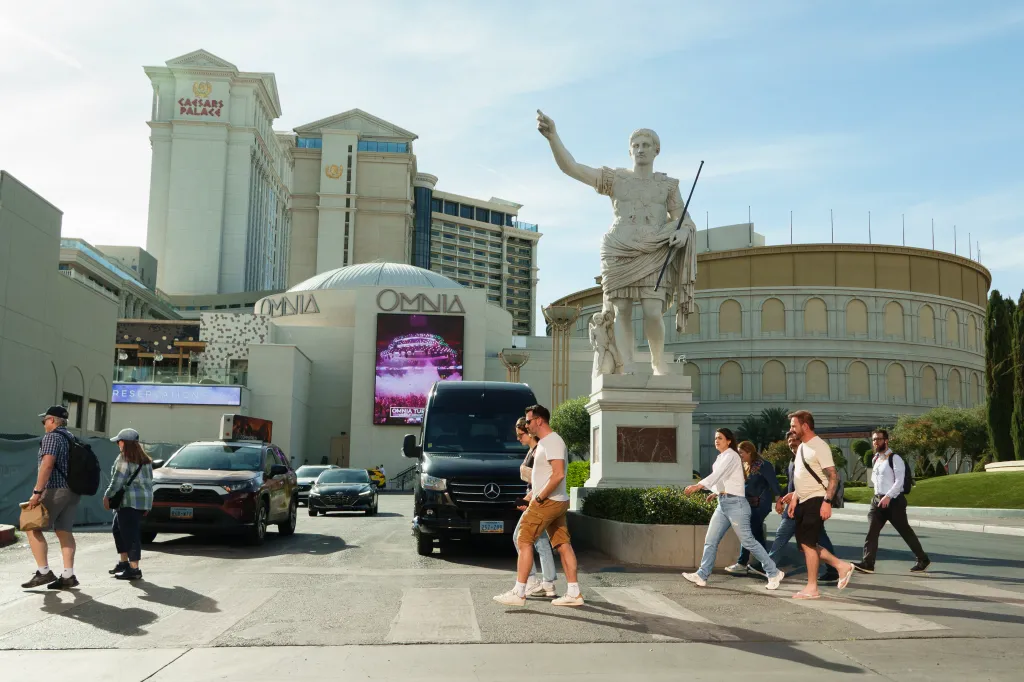 Tourists walk past Caesars Palace Hotel and Casino.