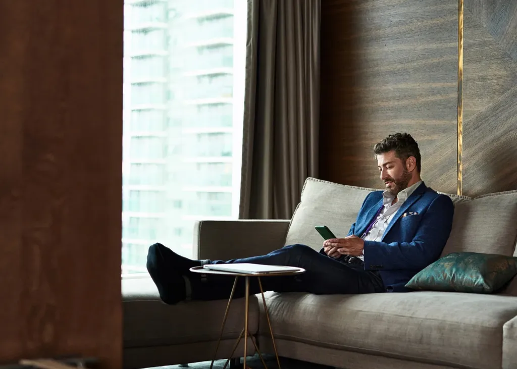 A man relaxing on a couch, looking at his phone.