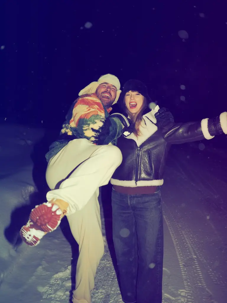 Travis Kelce carrying Taylor Swift in a snowy landscape at night.
