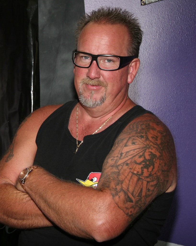 Darrell Sheets wearing a black tank top and glasses, with arms crossed.