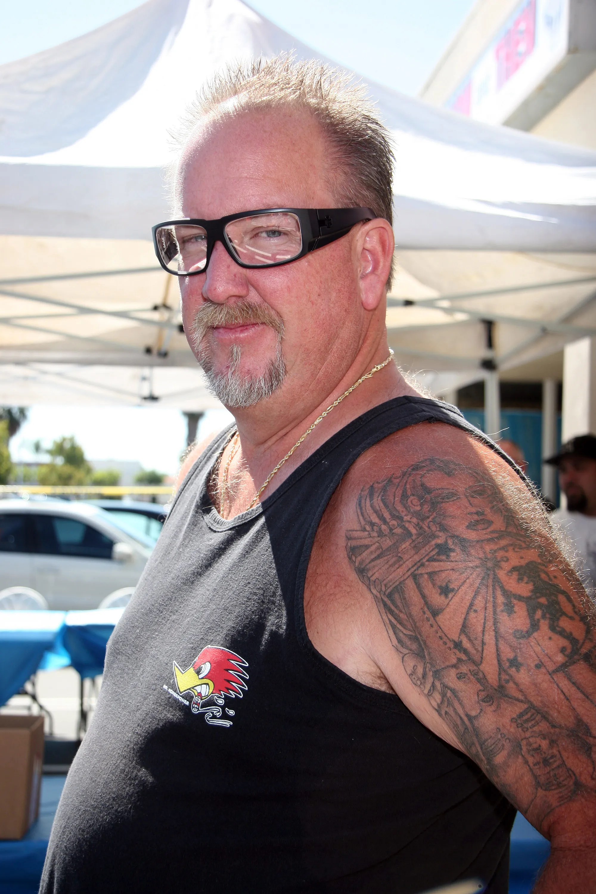 Darrell Sheets smiling while wearing a black tank top, gold chain, and glasses.