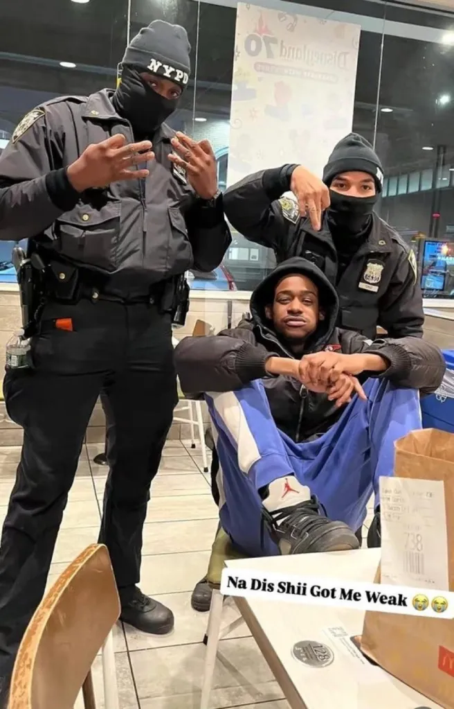 two masked cops throwing up what appear to be gang signs while a youngers sits