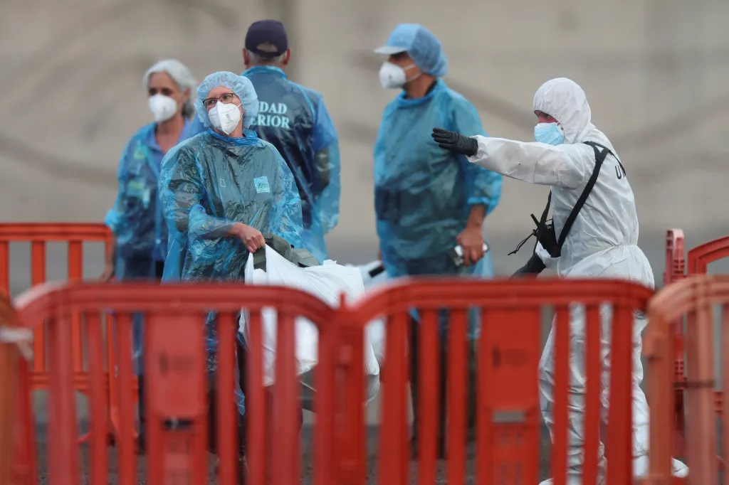 Personnel instructing cruise ship passengers affected by a hantavirus outbreak at the port of Granadilla de Abona.