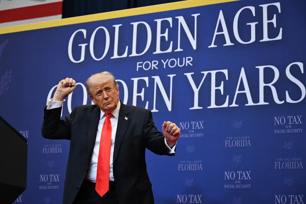 President Trump dances on stage in front of a blue backdrop that reads 