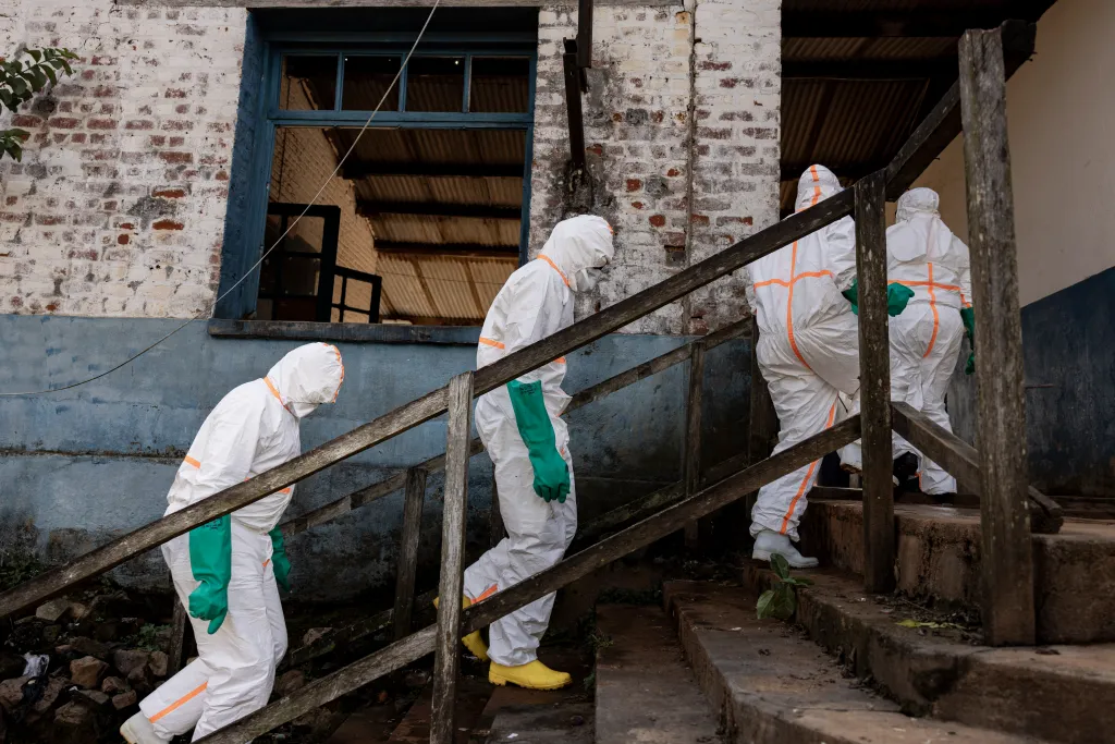 Workers in protective equipment ascending steps at the General Referral Hospital of Mongbwalu during an Ebola outbreak response.