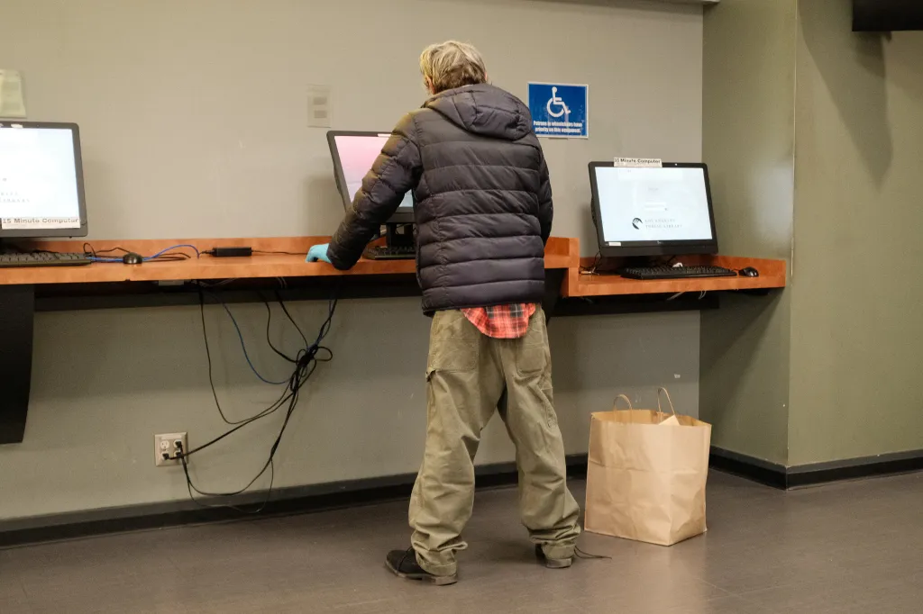 A person experiencing homelessness uses a 15-minute public computer at the Los Angeles Central Library.