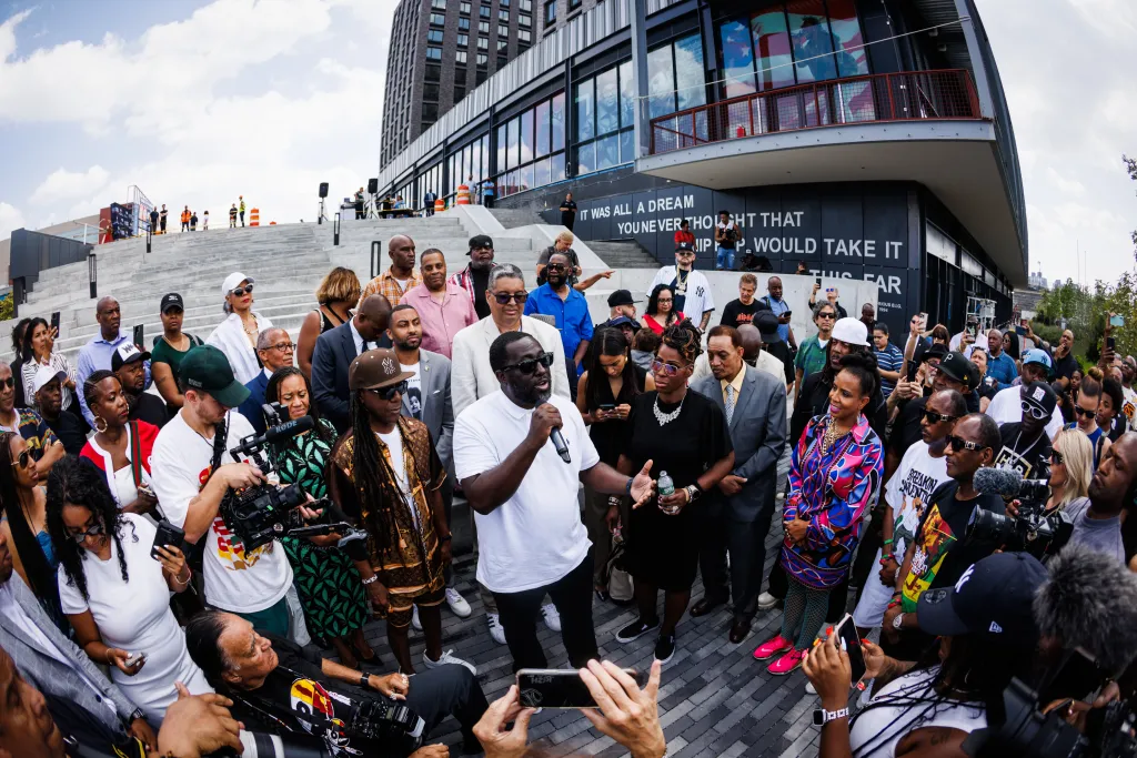 Rocky Bucano speaking at the Hip Hop 50th Birthday Jam at the Universal Hip Hop Museum in front of a crowd that includes Busy Bee and Bronx Borough President Vanessa L. Gibson.
