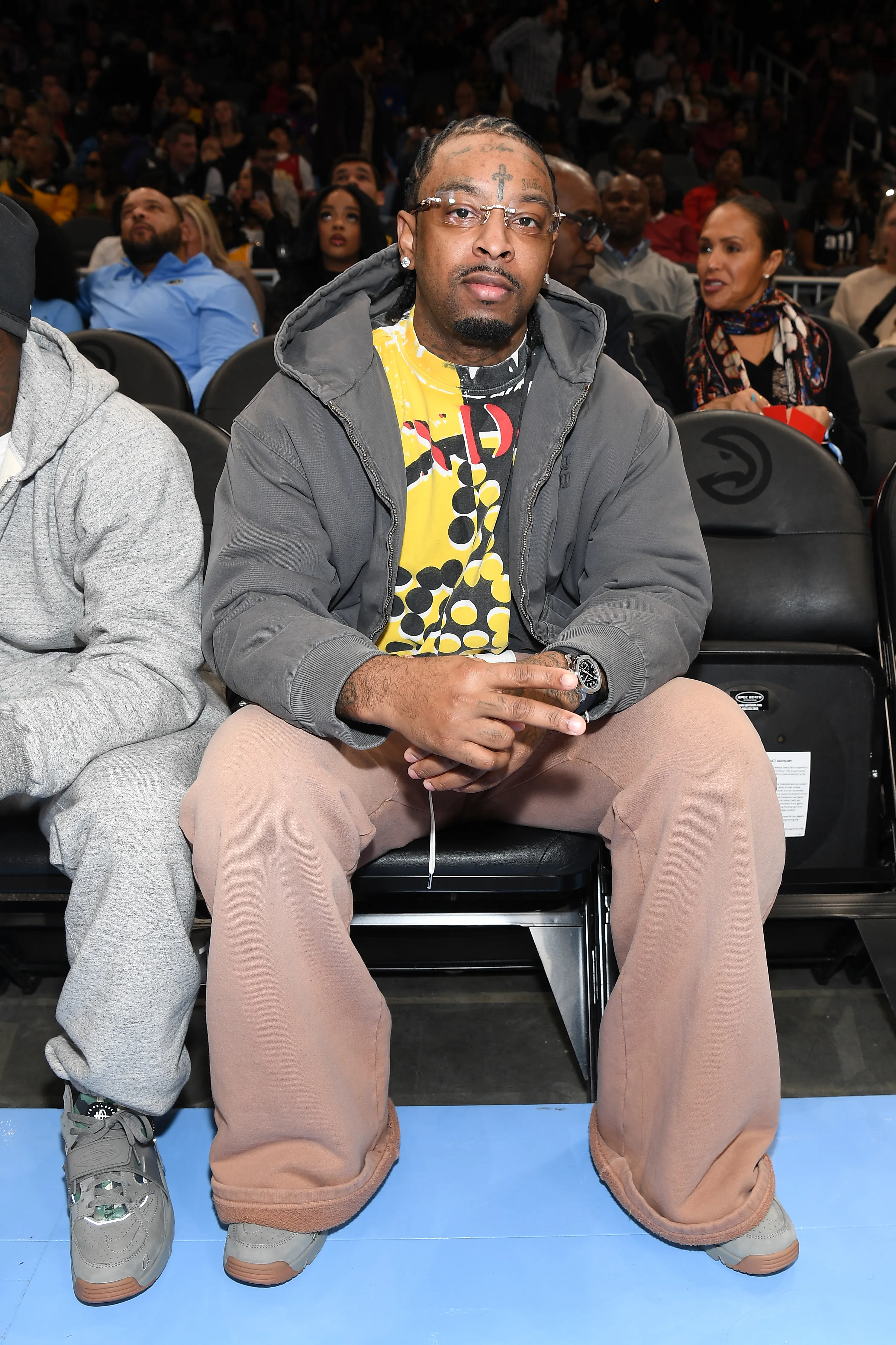 Rapper 21 Savage sitting courtside at a basketball game.