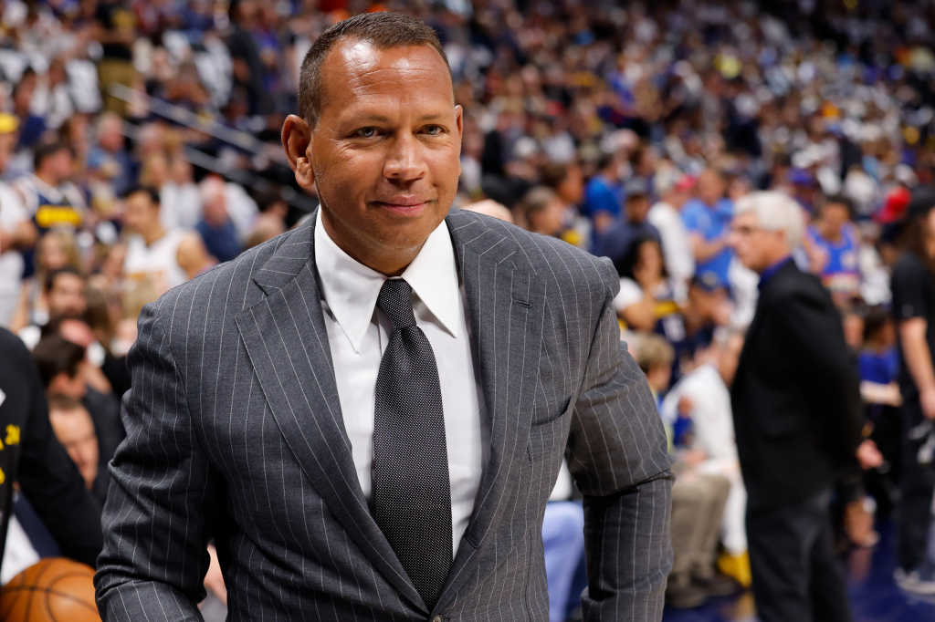 Former baseball player Alex Rodriguez in a pinstripe suit looking on at a basketball game.