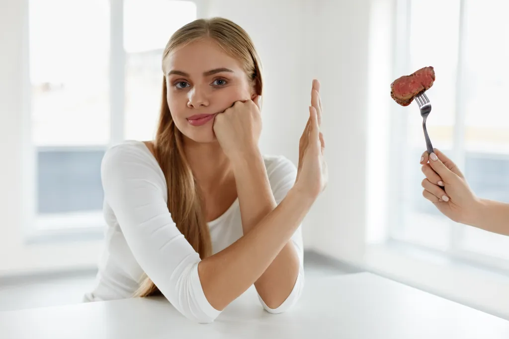 Woman rejecting a fork with a piece of meat.