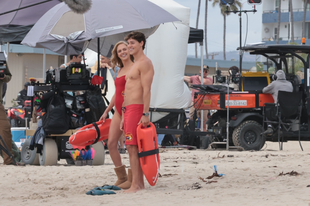Noah Beck and Jessica Belkin dressed as lifeguards, holding rescue buoys while filming