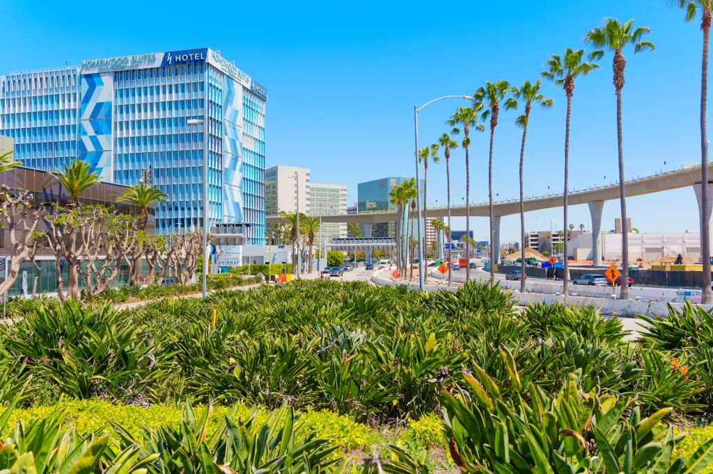 Homewood Suites by Hilton hotel near LAX with palm trees and an overpass.