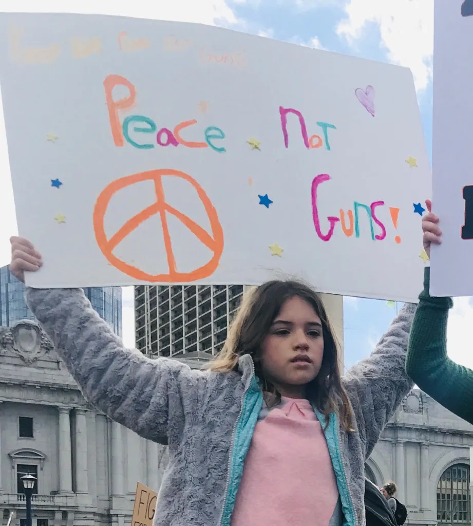 A young girl at a protest holding a sign that reads 